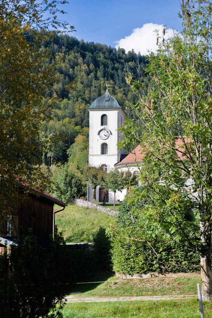 A charming church tower amidst lush greenery in the Swiss countryside.